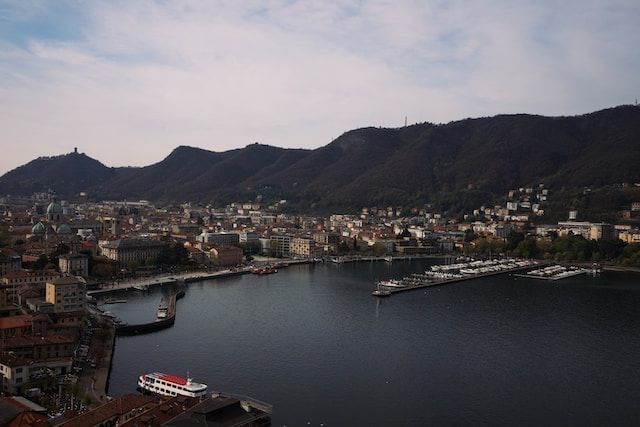 Postal del lago de Como rodeado de construcciones y montañas